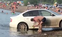 Водитель моет машину на пляже в Песчанке