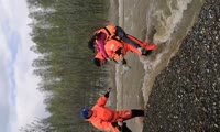 Спасатель переносит женщину через затопленную дорогу